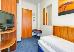 um quarto de hotel com uma cama e uma televisão de ecrã plano em Hotel am Friedensplatz em Stuttgart