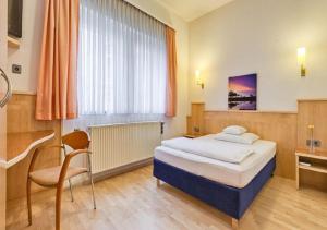 1 dormitorio con cama, escritorio y silla en Hotel am Friedensplatz en Stuttgart