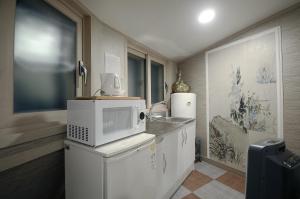 a kitchen with a microwave on top of a refrigerator at Family Hotel BNB in Busan