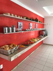 a kitchen with a red wall with shelves with food at Pousada Praia De Guarajuba in Guarajuba