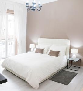 ミラノにあるDe Amicis Apartment Near Duomoの白いベッドルーム(大きな白いベッド1台、シャンデリア付)