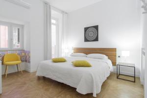 ナポリにあるSpaccanapoli Home Short Letsの白いベッドルーム(ベッド1台、黄色い椅子付)