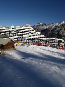 um edifício com neve no chão à sua frente em Val Gardena 1 em Puy-Saint-Vincent