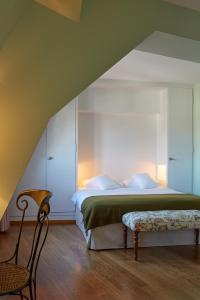 ein Schlafzimmer mit einem Bett, einem Stuhl und einer Bank in der Unterkunft hotel brasserie au violon in Basel