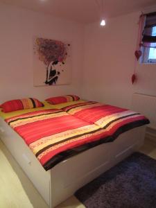 een bed in een slaapkamer met een rode en gele deken bij Christine Oparaugo - Privatzimmer mit Bad in Leutkirch im Allgäu