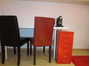 einen Schreibtisch mit 2 Stühlen und einer roten Kommode in der Unterkunft Christine Oparaugo - Privatzimmer mit Bad in Leutkirch im Allgäu