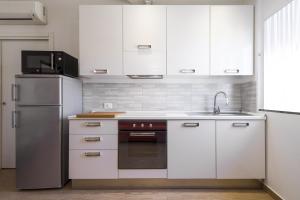 La cuisine est équipée de placards blancs et d'un réfrigérateur en acier inoxydable. dans l'établissement PrimoPiano - Melzo A, à Milan