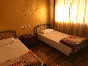 1 dormitorio con 2 camas y una ventana con cortinas en Sun Rise Hotel & Hostel & Tours, en Amán