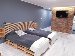 2 camas en una habitación con TV en una pared de ladrillo en Apartament Panorama, en Kielce