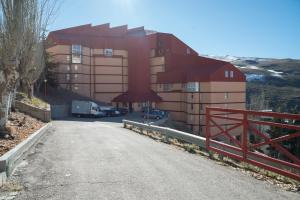 a building with a red fence on the side of a road at Fabuloso Apartamento En Sierra Nevada in Sierra Nevada