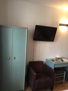 a room with a chair and a tv on the wall at Hotel Des Falaises in Étretat