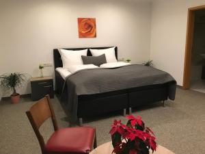 a bedroom with a bed and a red chair at Pension Scheiber Hof in Neunkirchen