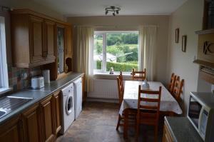 cocina con mesa, fregadero y ventana en Drumahaman Cottage en Ballycastle