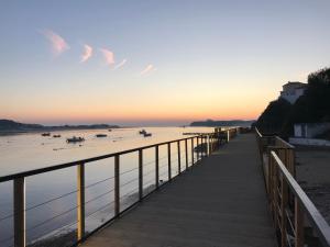 a boardwalk leading to a beach with boats in the water at PIER HOUSES by Nature Bliss in Vila Nova de Milfontes