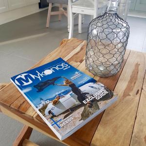 a magazine sitting on top of a wooden table at Antheia Suite of Mykonos in Ano Mera