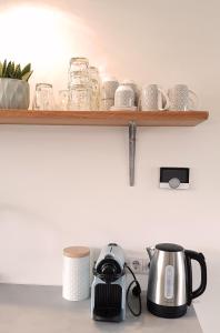 a shelf with glasses and a tea kettle on a counter at INTIKA Beach House in Zandvoort