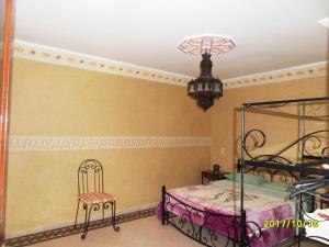 a bedroom with a bed and a chair and a chandelier at Appartement Terrasse Beau Soleil in Essaouira