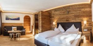 a bedroom with a large bed with a wooden wall at Almhof Kitzlodge - Alpine Lifestyle Hotel in Kirchberg in Tirol