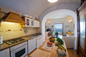 a kitchen with white cabinets and a table with fruit on it at Mon Amour Praiano in Praiano