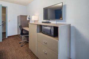 um quarto de hotel com uma secretária e uma televisão numa cómoda em Silicon Valley Inn em Belmont