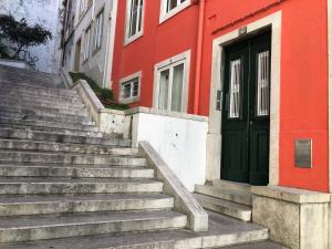 schody prowadzące do czerwonego budynku z zielonymi drzwiami w obiekcie Encantadora Casa do Limoeiro w Lizbonie