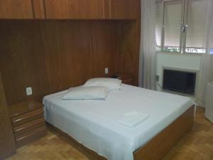 1 dormitorio con 1 cama blanca grande y TV en City Hotel PF, en Passo Fundo