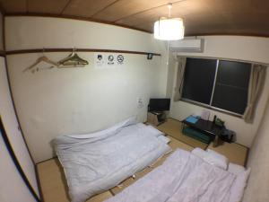 Una pequeña habitación con una cama y una ventana. en Kenroku Haitsu 303, en Kanazawa