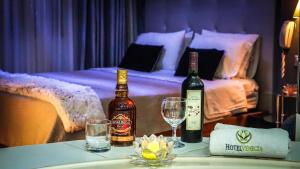 two bottles of wine and glasses on a table with a bed at Hotel Venecia in Huánuco