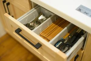 a drawer in a cabinet filled with utensils at Guesthouse Kintoto in Kanazawa