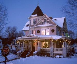 una casa decorata con luci di Natale nella neve di White Lace Inn a Sturgeon Bay