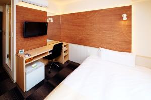 a hotel room with a bed and a desk and a tv at Super Hotel Ogaki Ekimae in Ogaki