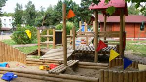 a playground with a wooden bridge and some flags at POLONEZ - domki letniskowe in Dąbki