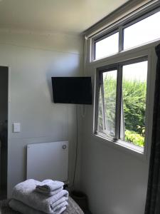 a bedroom with a television and a bed with towels at 40 Winks in Otorohanga