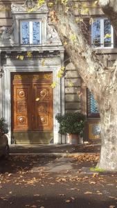 una gran puerta de madera en un edificio con un árbol en Via Veneto Luxury Suites, en Roma