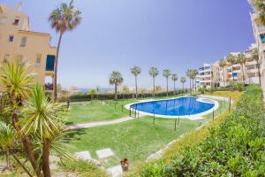 an image of a swimming pool in a yard with palm trees at Casinomar Frente al Mar in Benalmádena