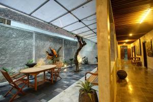 a patio with a table and chairs and a wall at Watu Agung Guest House in Borobudur