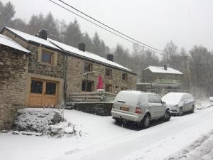 two cars parked in front of a house in the snow at Lesse matinal in Redu