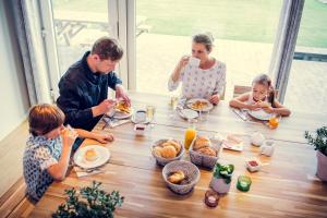 una familia sentada alrededor de una mesa desayunando en De Schaapskooi, en Kasterlee