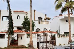 a white house with palm trees in front of it at Aux Moules de Harhoura Rabat in El Harhoura