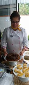 a woman standing in front of a table with plates of food at Pousada by Rieger in Blumenau