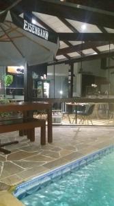 a swimming pool with a table and an umbrella at Pousada by Rieger in Blumenau