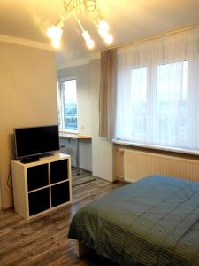 a bedroom with a bed and a flat screen tv at Grey Apartament Centrum Gdynia in Gdynia