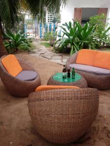 four wicker chairs and a table with bottles on it at Résidence Tichani Club in Cotonou