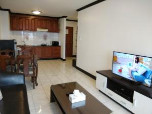 ein Wohnzimmer mit einem TV und einer Küche in der Unterkunft Patong Tower by United 21 Thailand in Patong Beach