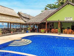 a resort with a swimming pool next to the ocean at Lanta New Beach Bungalows - SHA Plus in Ko Lanta