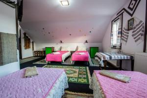 three beds in a room with pink sheets at Casa Lia in Valea Putnei