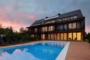 a large house with a swimming pool in front of it at Klonova in Białogóra