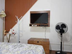 - une chambre avec une télévision, un ventilateur et un lit dans l'établissement Apartamento no Centro de Canela, à Canela