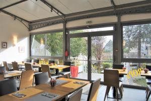 a restaurant with tables and chairs and large windows at Logis Hôtel de l'Europe in Poitiers