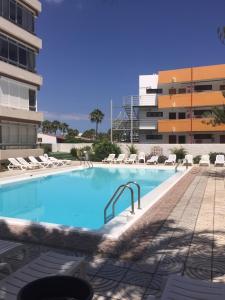 a large swimming pool with chairs and a building at Premium Apartment Yumbo WIFI A/C in Playa del Ingles